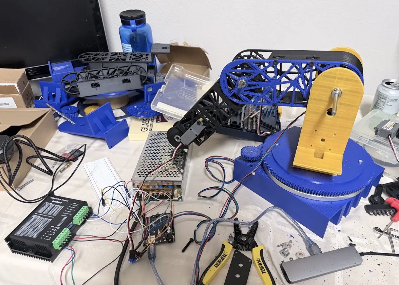 Integrated robotic arm prototype on a workbench with electronics and wiring